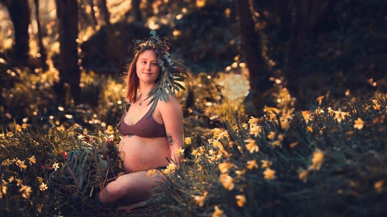 Rosa at nearly 9 months pregnant in the woods at sunset with flowers in her hair